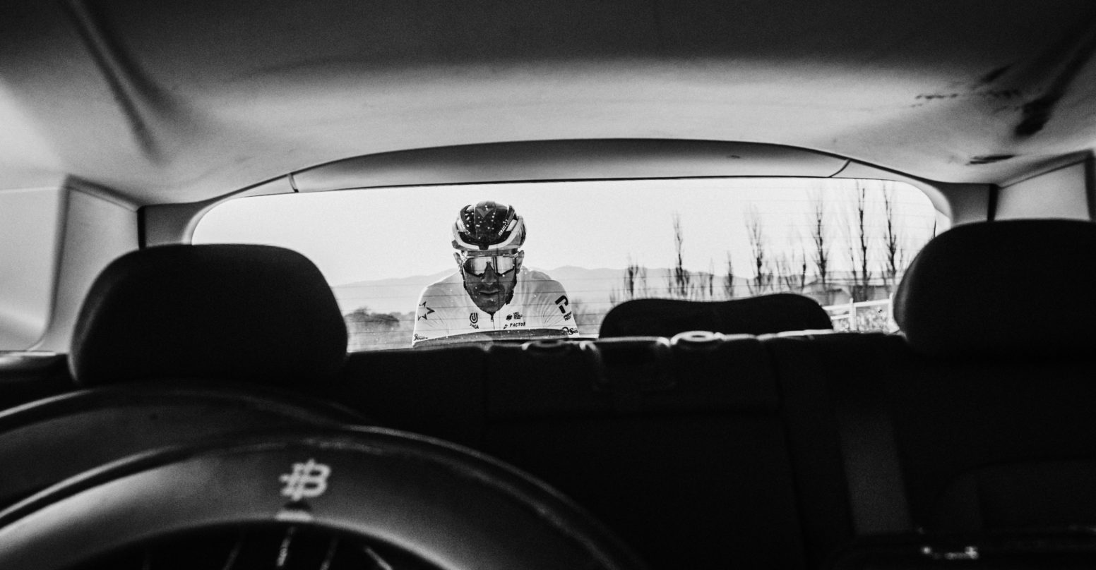 Rider seen through the back window of the team car